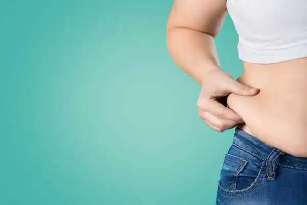 Image of woman pinching her love handles to show weight gain Crawley